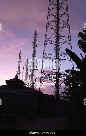 Il palo della torre BTS o il trasmettitore radio svettano in alto nel cielo al mattino Foto Stock