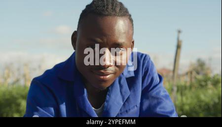 Ritratto di un giovane agricoltore afroamericano in un campo agricolo biologico, che controlla le colture Foto Stock