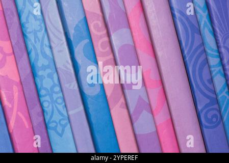 Una fila di libri colorati con motivi diversi. Alcuni sono blu, altri rosa, e altri viola Foto Stock
