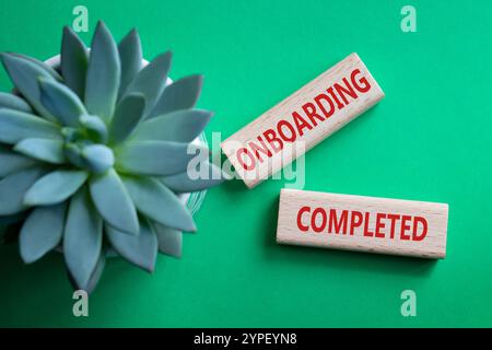 Simbolo onboarding completato. Termine concettuale onboarding completato su blocchi di legno. Splendido sfondo verde con piante succulente. Business e a bordo Foto Stock