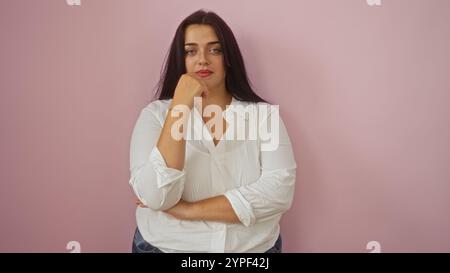 Donna giovane e sicura di sé con la camicia bianca si staglia su sfondo rosa con un'espressione premurosa. Foto Stock