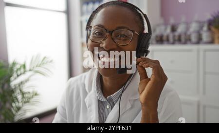 Donna sorridente in farmacia che indossa cuffie e cappotto bianco, impegnata nel servizio clienti. Foto Stock