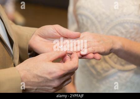 Primo piano di un Groom che mette l'anello nuziale sul dito della sposa - momento romantico del giorno delle nozze Foto Stock