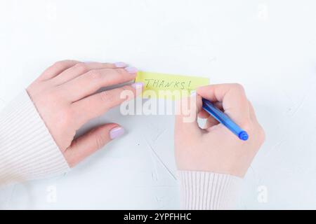 Una giovane donna crea una nota di ringraziamento scritta a mano. Copia spazio. Foto Stock