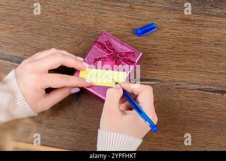 Giovane donna che scrive la nota di ringraziamento sulla confezione regalo. Copia spazio. Foto Stock