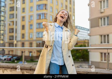 Oh mio Dio, wow. Donna matura caucasica che sembra sorpresa, scioccata da una vittoria improvvisa, vittoria di una partita, raggiungimento di un obiettivo della lotteria, buone notizie all'aperto. Ragazza eccitata che stringe pugni sulla strada del centro città. Foto Stock