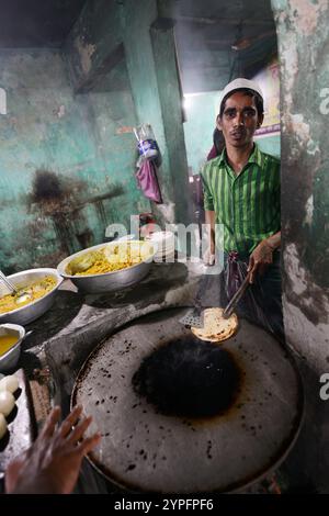 Un uomo bengalese che prepara roti freschi in un piccolo ristorante a Dacca, Bangladesh. Foto Stock