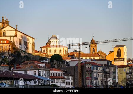 Porto, Portogallo - 28 luglio 2024: Edifici urbani durante l'ora del tramonto, con un edificio con il logo della cantina Sandeman. Foto Stock