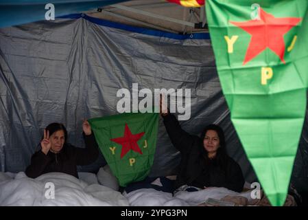 Londra, Regno Unito. 30 novembre 2024. Sara ha (a destra) 50 anni e Berivan Yavli (a sinistra) 55 anni gli scioperanti della fame hanno una bandiera YPJ vicino al Kurdish Community Centre di Londra. YPJ significa unità di protezione delle donne in inglese e Yekineyen Parastina Yin in curdo. Sei curdi hanno iniziato uno sciopero della fame 4 giorni fa a Londra nord, vicino al Kurdish Community Centre. A causa del raid della polizia nell'edificio che si è concluso con 7 arresti. Secondo la polizia si collegano al gruppo militante bandito chiamato Partito dei lavoratori del Kurdistan (PKK). Credito: SOPA Images Limited/Alamy Live News Foto Stock