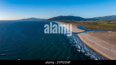 Veduta aerea di Tarifa, Spagna, con spiaggia sabbiosa, Oceano Atlantico e verdi colline. La costa curva dolcemente sotto un cielo limpido con onde dolci Foto Stock