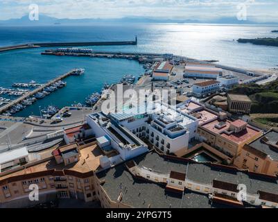 L'immagine mostra una vista aerea di Tarifa, Spagna, con un vivace porto con barche e yacht, circondato da edifici moderni e tradizionali. Foto Stock