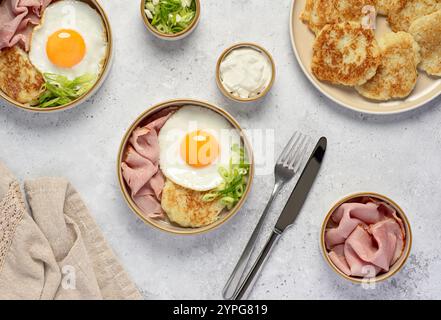 Fotografia gastronomica di uova fritte con frittelle di patate, prosciutto arrosto e cipolla primaverile; yogurt, colazione, brunch Foto Stock