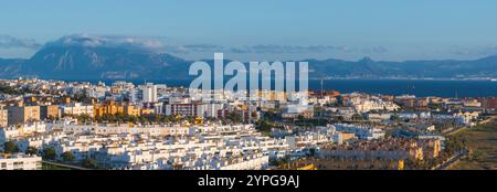 Vista aerea di Tarifa, Spagna, caratterizzata dall'architettura andalusa, dallo stretto di Gibilterra e dalle lontane montagne marocchine sotto un cielo azzurro. Foto Stock