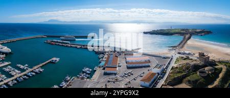 Vista aerea di Tarifa, Spagna, con un vivace porto con barche, un traghetto, spiagge sabbiose, Isla de las Palomas con un faro e lo stretto di Foto Stock