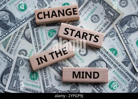 Il cambiamento inizia dal simbolo della mente. Le parole concettuali cambiano iniziano nella mente sui blocchi di legno. Bellissimo sfondo di dollari. Il business e il cambiamento iniziano da qui Foto Stock