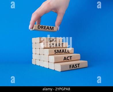 Simbolo Dream Big Start Small Act Fast. Parole concettuali Dream Big Start Small Act Fast su blocchi di legno. Mano d'affari. Bellissimo sfondo blu. Autobus Foto Stock