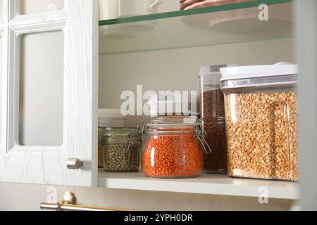 Diversi tipi di cereali e legumi in contenitori nell'armadio Foto Stock