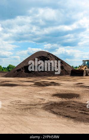 Pali di compost, realizzati con concime di mucca, vengono trasformati e accatastati nello stabilimento di produzione del Michigan, USA. Foto Stock