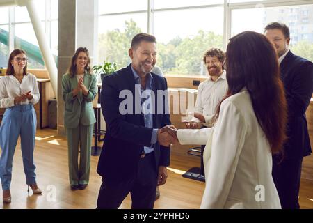 Colleghi felici che stringono la mano alla riunione in ufficio, celebrando il successo o i risultati aziendali. Foto Stock