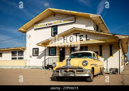 Un'auto gialla è parcheggiata di fronte a un hotel. L'hotel e' vecchio e presenta uno schema colore giallo e bianco Foto Stock