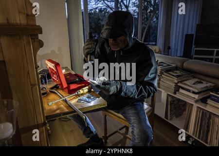 Immagine simbolica di un ladro, l'esecutore ha rotto in un appartamento dal lato del giardino e sta cercando bottino, apre una cassa, trova oggetti di valore Foto Stock