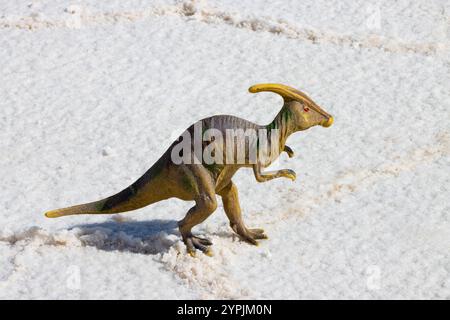 Dinosauro giocattolo sulla superficie salina bianca di Salar de Uyuni, Bolivia, creando un contrasto stravagante e giocoso nelle vaste distese saline. Foto Stock