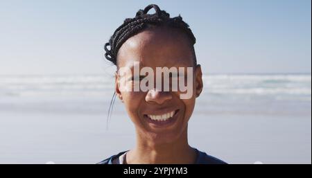 Ritratto di una donna afroamericana attraente che si diverte ad allenarsi in spiaggia in una giornata di sole, pratto Foto Stock