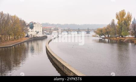 Fiume Moldava in una giornata nebbiosa con vista sul Ponte Carlo e sugli edifici medievali di Praga. Foto Stock