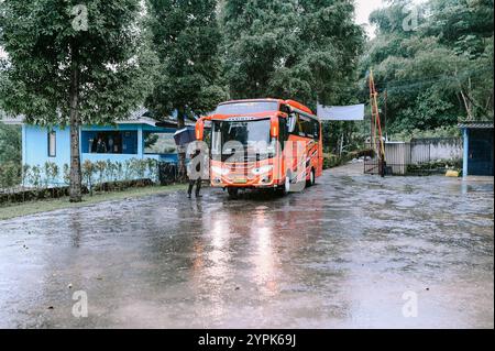 Bogor, 18 novembre 2024. Un autobus rosso entra nell'area parcheggio di una villa, circondato da vegetazione lussureggiante e dintorni panoramici Foto Stock