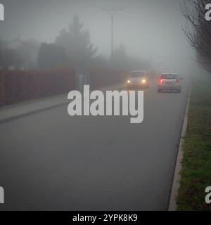 Vettura che viaggia su strade nebbiose con fari o fari accesi. Bassa visibilità - guida pericolosa delle auto in inverno in condizioni meteorologiche avverse Foto Stock