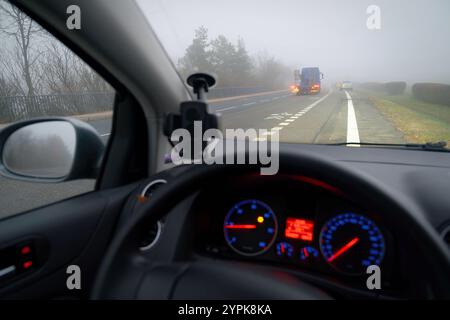 Vettura che viaggia su strade nebbiose con fari o fari accesi. Bassa visibilità - guida pericolosa delle auto in inverno in condizioni meteorologiche avverse Foto Stock