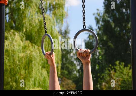 La persona tiene le mani sugli anelli da ginnastica all'aperto. Primo piano. Foto Stock