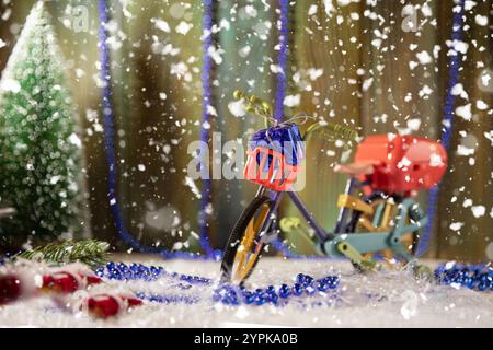Bicicletta giocattolo colorata con confezione regalo e decorazioni natalizie sullo sfondo delle feste Foto Stock