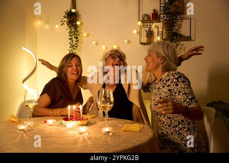 Donne anziane che festeggiano il compleanno, ridono e si divertono a una festa a casa Foto Stock