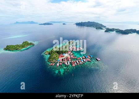 Stupefacente vista aerea con drone di un remoto villaggio su palafitte Bajau costruito sopra un vibrante laguna turchese nell'ammirevole arcipelago di Sombori. Foto Stock