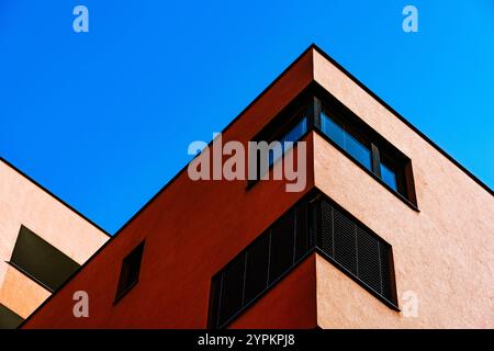 Vivace angolo degli edifici con facciata rossa e gialla a contrasto e finestre riflettenti Foto Stock