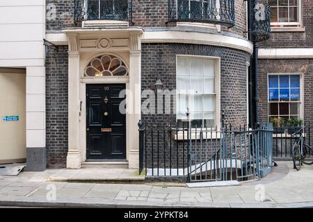 Storica residenza cittadina di Londra con elegante porta nera numero 10, caratterizzata da architettura georgiana con ventaglio luminoso e porta ornata in pietra Foto Stock