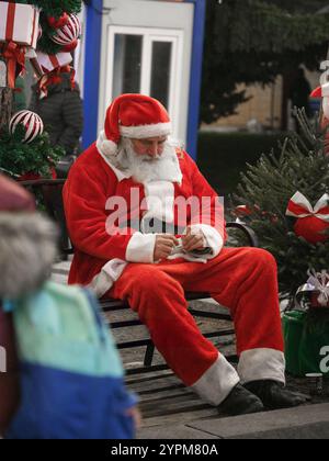 Vecchio Babbo Natale con cappello seduto al mercatino di Natale di Sofia, Bulgaria. Foto Stock