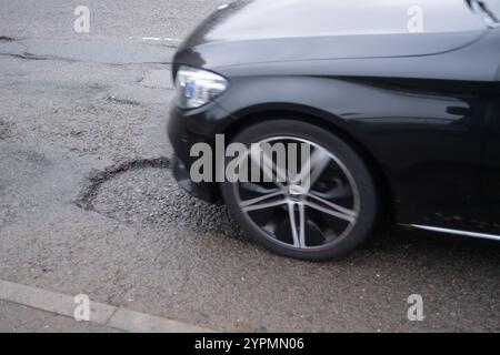 Taplow, Regno Unito. 30 novembre 2024. Le buche sono riapparse a Marsh Lane, Taplow, Buckinghamshire. Alcuni automobilisti cercano di evitarli. Le riparazioni alle buche precedenti su questo tratto di strada sono state effettuate nel maggio 2023 da appaltatori del Buckinghamshire Council che hanno utilizzato un nuovo sistema Velocity Patching per riempire migliaia di buche stradali attraverso Bucks. Il Velocity patcher spinge l'aria ad alta velocità in buche per liberarli, quindi l'area viene ricoperta di bitume freddo per creare una tenuta, prima che l'aggregato venga rivestito in bitume e applicato, di nuovo ad alta velocità. Le riparazioni invece no Foto Stock