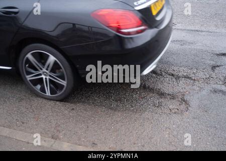 Taplow, Regno Unito. 30 novembre 2024. Le buche sono riapparse a Marsh Lane, Taplow, Buckinghamshire. Alcuni automobilisti cercano di evitarli. Le riparazioni alle buche precedenti su questo tratto di strada sono state effettuate nel maggio 2023 da appaltatori del Buckinghamshire Council che hanno utilizzato un nuovo sistema Velocity Patching per riempire migliaia di buche stradali attraverso Bucks. Il Velocity patcher spinge l'aria ad alta velocità in buche per liberarli, quindi l'area viene ricoperta di bitume freddo per creare una tenuta, prima che l'aggregato venga rivestito in bitume e applicato, di nuovo ad alta velocità. Le riparazioni invece no Foto Stock