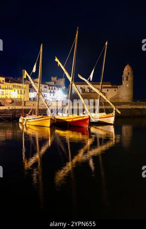 Colorate barche a vela sulla passeggiata illuminata nel porto della città vecchia di Collioure di notte, Cote Vermeille, Francia Foto Stock