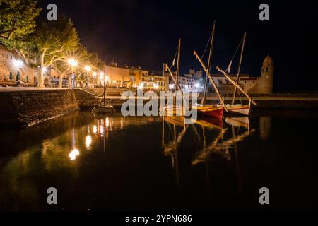 Colorate barche a vela sulla passeggiata illuminata nel porto della città vecchia di Collioure di notte, Cote Vermeille, Francia Foto Stock