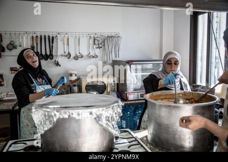 Beirut, Libano. 21 novembre 2024. Le donne sfollate dalla guerra in Libano cucinano cibo per altri sfollati in un centro di accoglienza gestito dalla ONG Mouvement Social a Bourj Hammoud, Beirut. Israele lanciò una delle più intense campagne aeree della storia contemporanea contro il gruppo militante libanese Hezbollah dal settembre 2024, in particolare mirando ai sobborghi meridionali di Beirut tra le altre aree del paese. (Credit Image: © Sally Hayden/SOPA Images via ZUMA Press Wire) SOLO PER USO EDITORIALE! Non per USO commerciale! Foto Stock