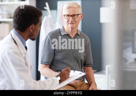 Ritratto di uomo anziano caucasico che parla con il medico durante la consultazione in clinica e che spiega i sintomi e le preoccupazioni per la salute, copia spazio Foto Stock
