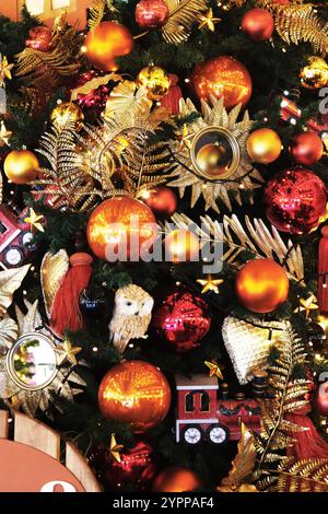 Molti giocattoli diversi sul primo piano dell'albero di Capodanno...decorazioni natalizie per il design. Giocattoli rossi e arancioni sull'albero di Natale. Foto Stock