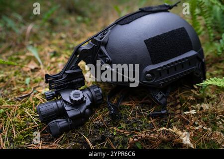 Casco balistico con visione notturna monoculare giace a terra. Foto Stock