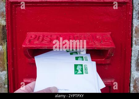 Pubblicazione di buste stampate di Natale di seconda classe in una casella postale del Regno Unito. Postare le cartoline di Natale. Foto Stock