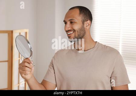 Uomo sorridente che guarda lo specchio in camera Foto Stock