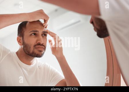 Uomo preoccupato che guarda lo specchio in bagno Foto Stock