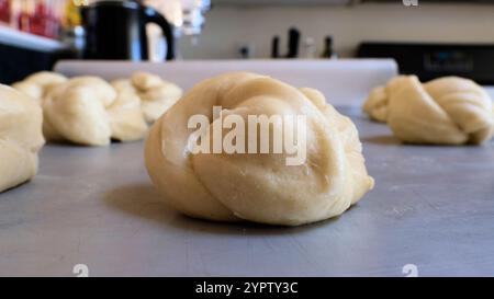 I panini di lievito per la cena sono legati a nodi e poggiano su un foglio di cottura in metallo, dimostrando che l'impasto si solleva prima di cuocere in forno. Foto Stock
